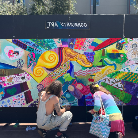 student and artist painting a mural